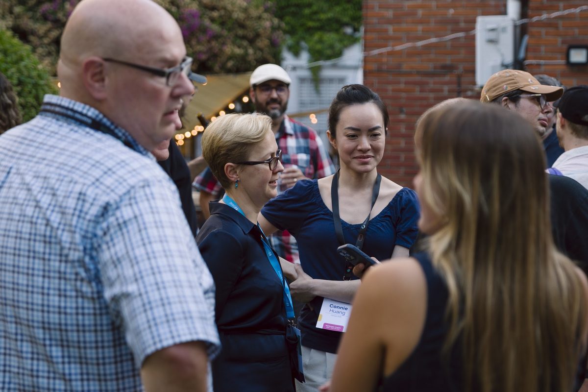 A small group deep in conversation outside the venue during Summer Week 2026