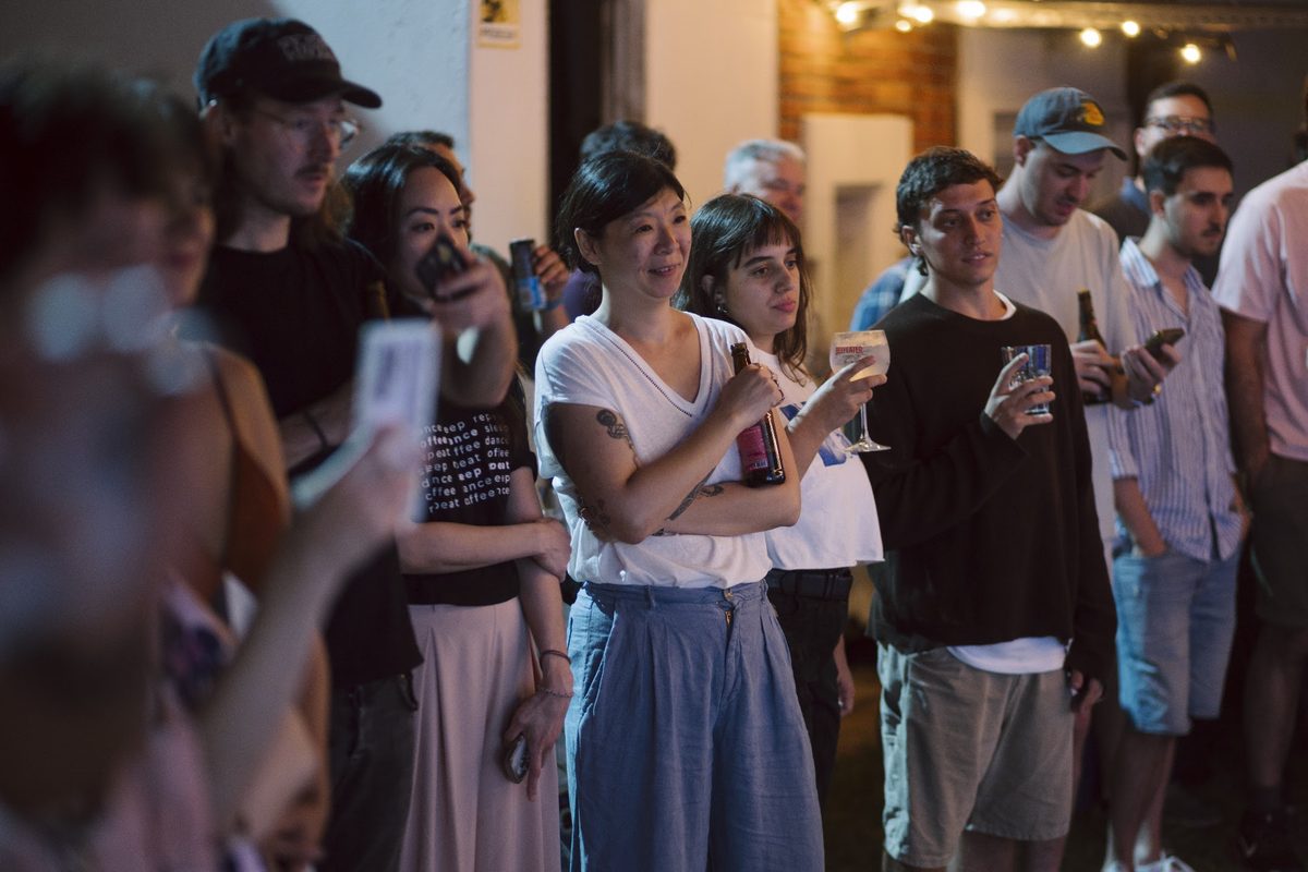 Campers with drinks in hand, talking in a lantern-lit passage during Summer Week 2026