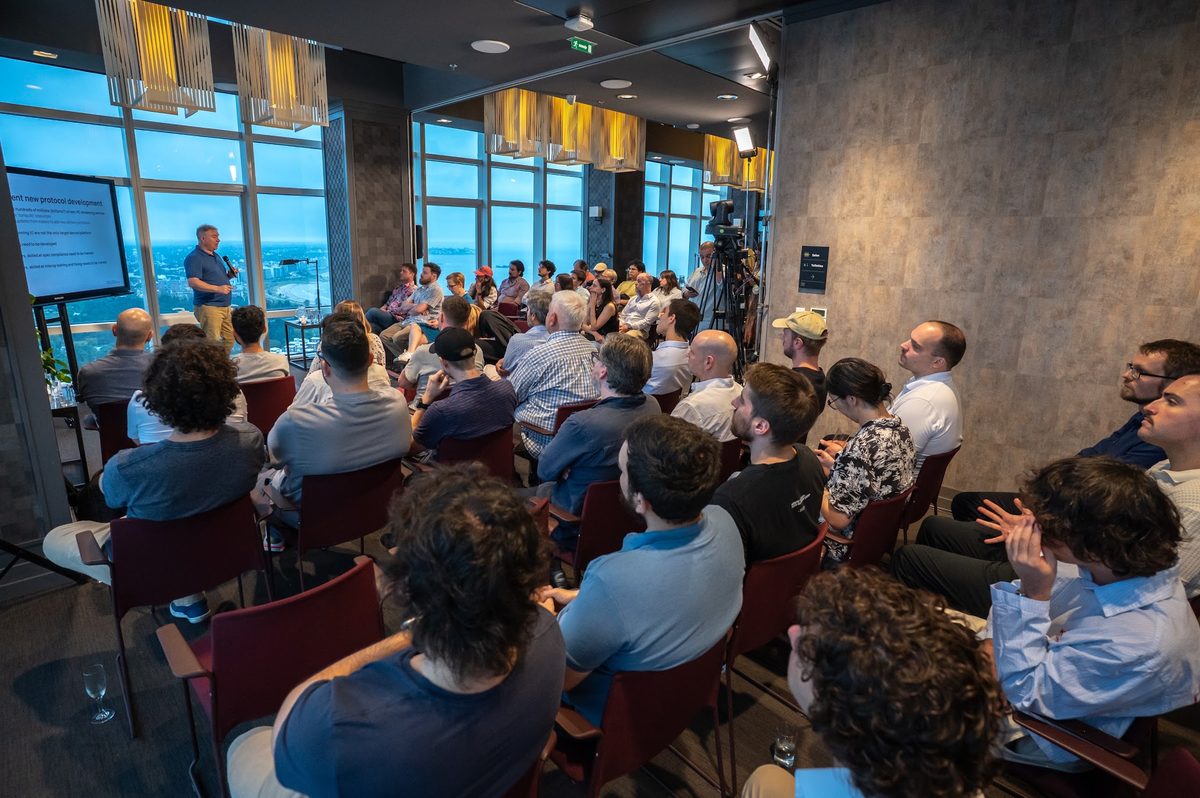 A full room at the last edition during a talk, with Montevideo and the river through the windows