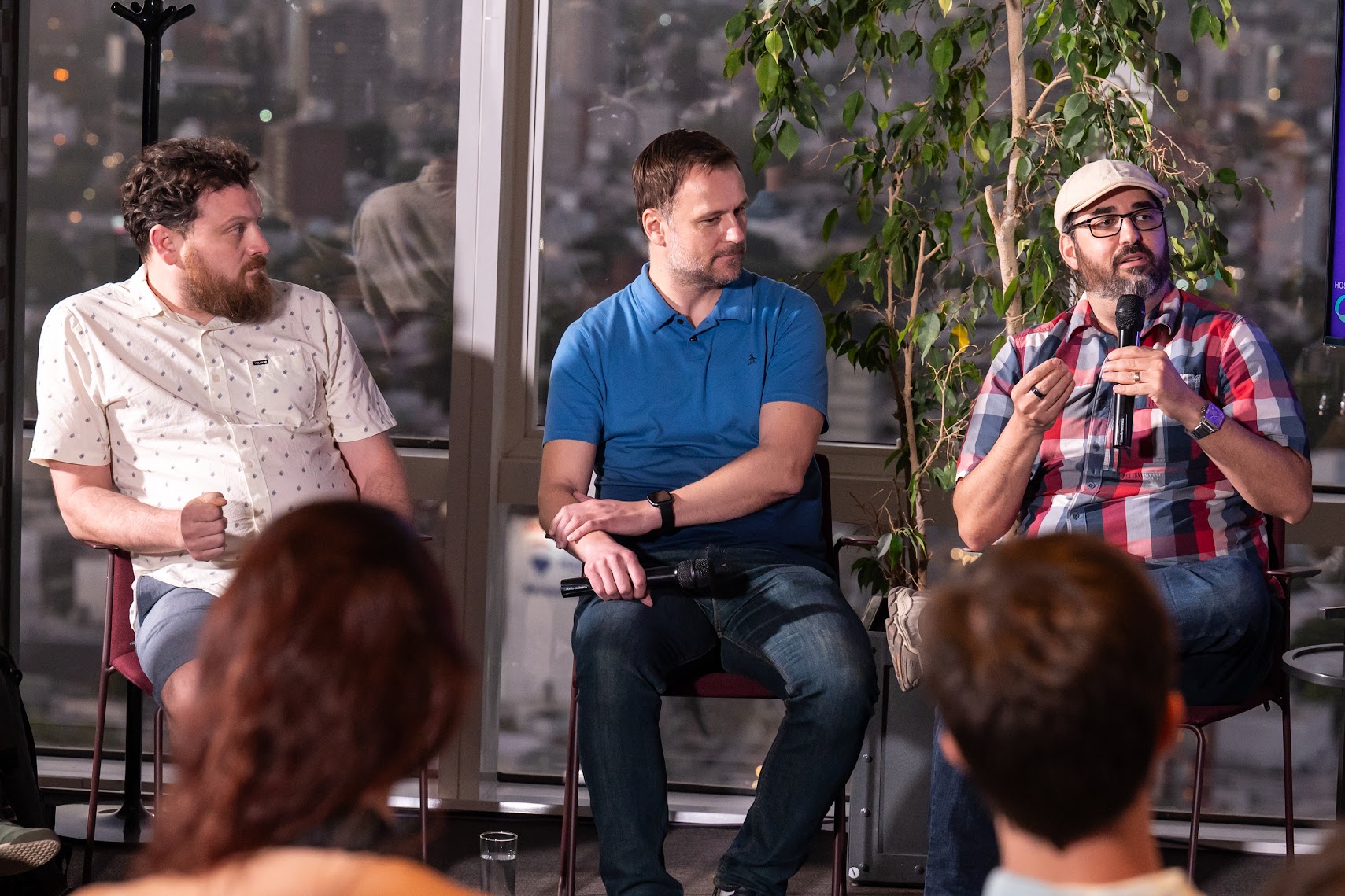 Three panellists on stage during a MonteVIDEO Tech Day discussion, one speaking into a microphone