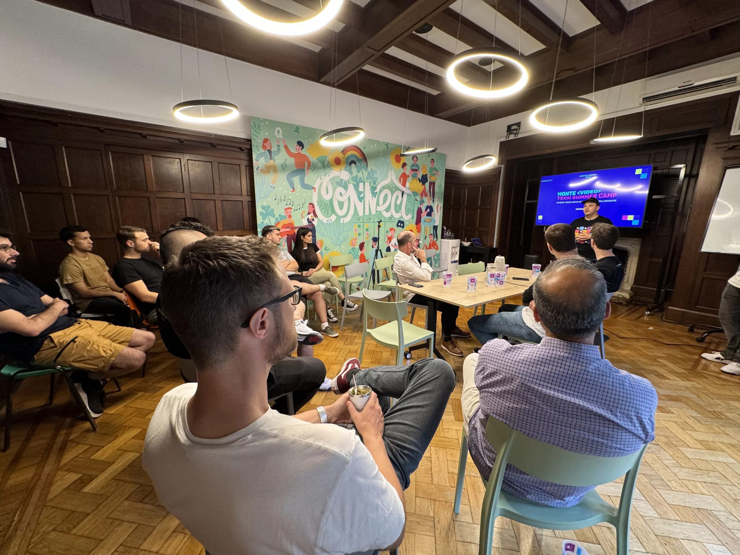 A meetup session in a room with a colourful mural on the wall