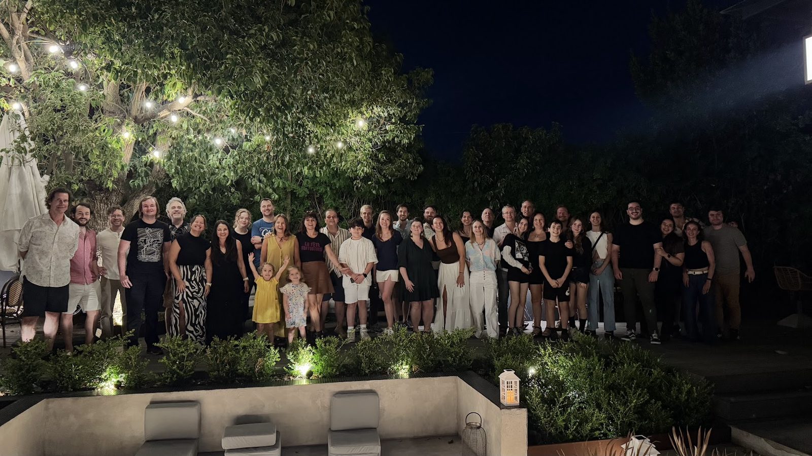 The whole Summer Camp group posing together at the closing party, under strings of lights