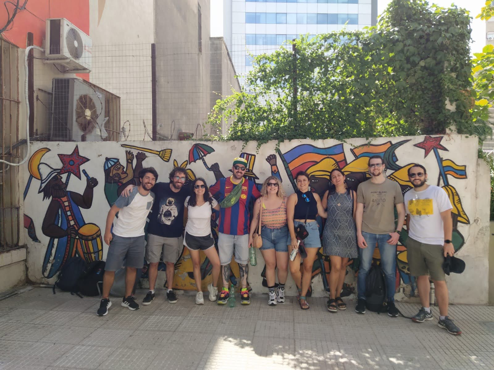 Summer Camp participants posing in front of a street mural in Montevideo