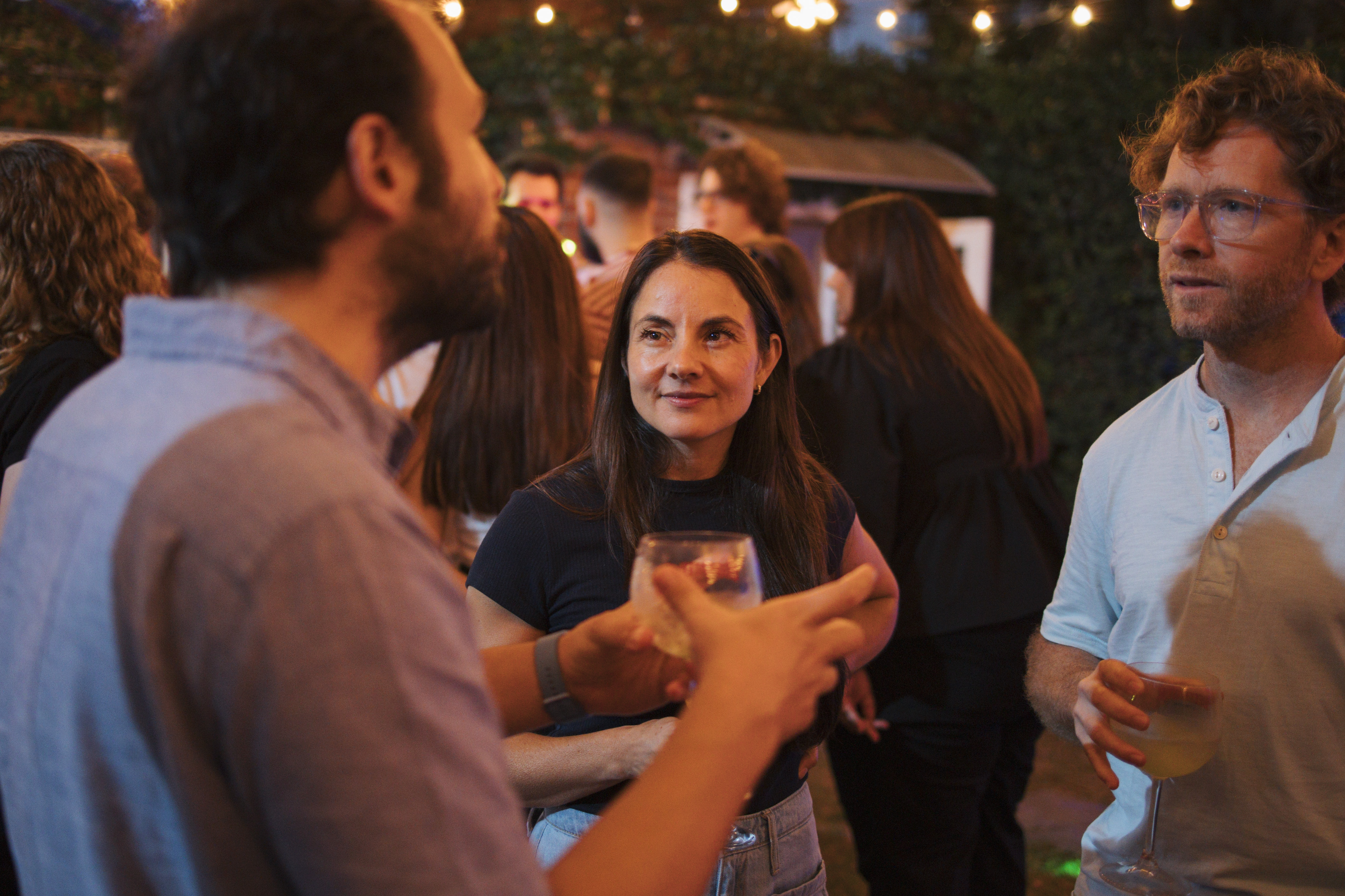 Attendees chatting with drinks in hand at an evening garden gathering